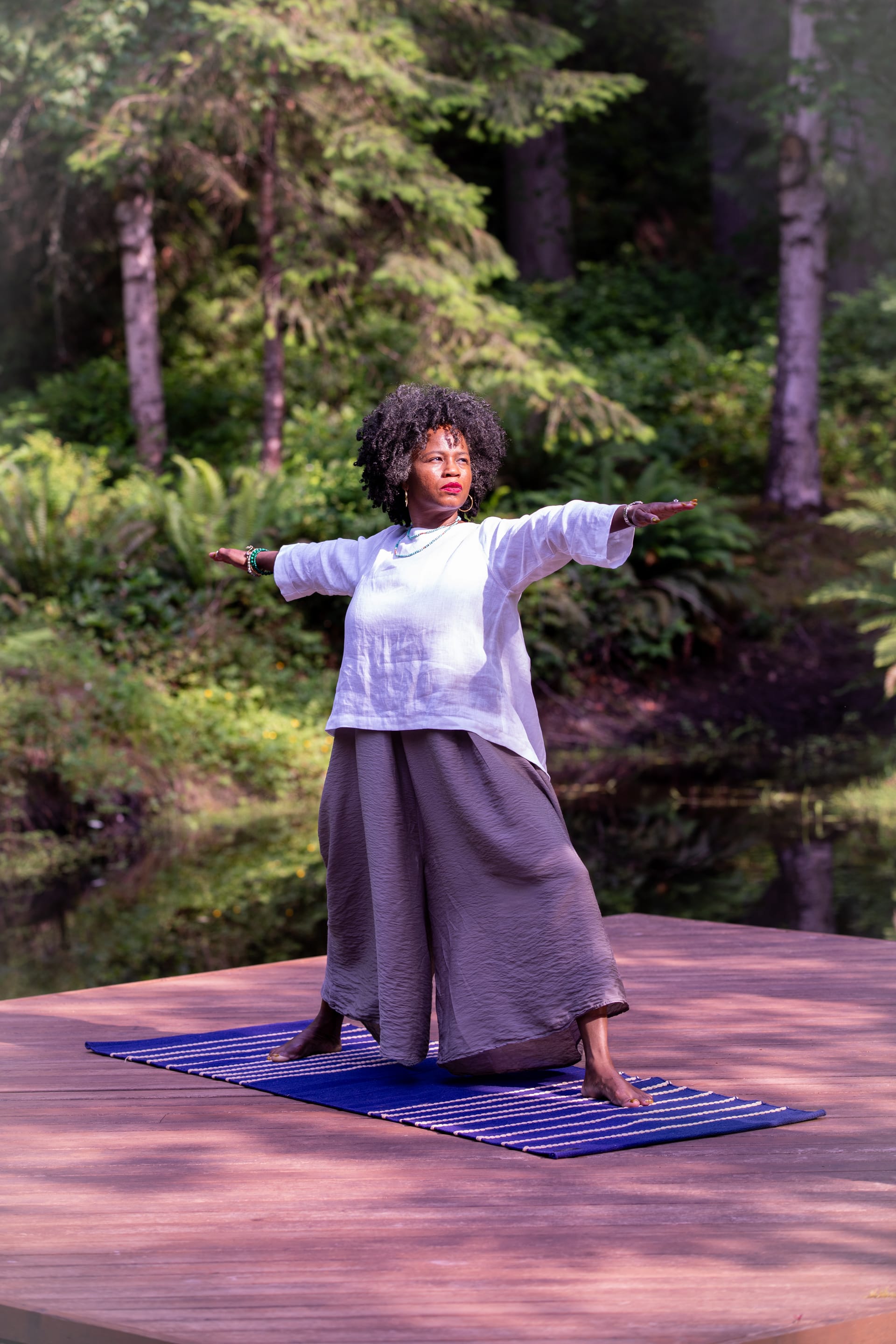 Woman practicing yoga outdoors surrounded by summer greenery